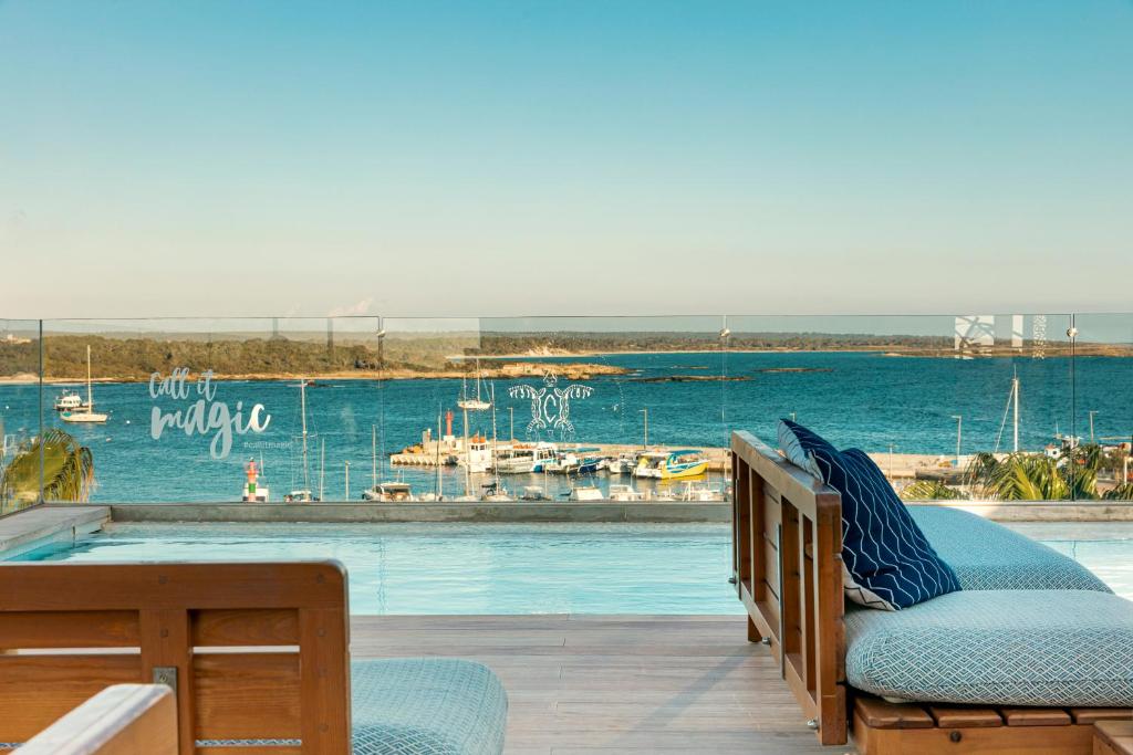 The rooftop infinity pool at Honucai in golden light, its edge meeting the sea, sun loungers along the deck and the boats of the marina just beyond the water