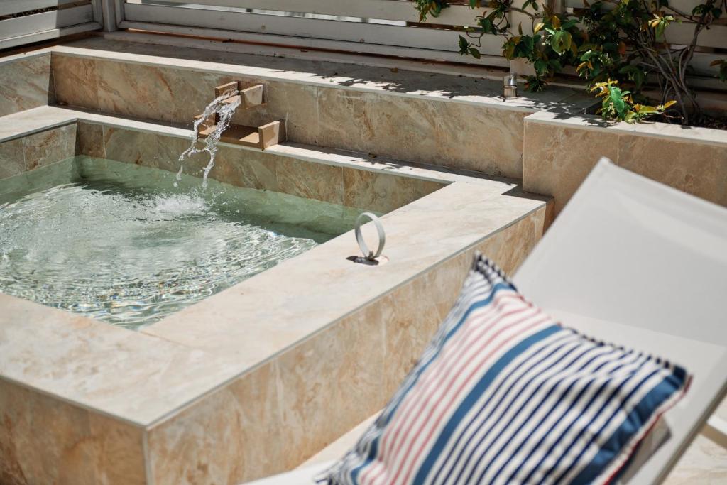 The shaded plunge pool and sun terrace below, a blue-striped towel folded on a lounger by the water