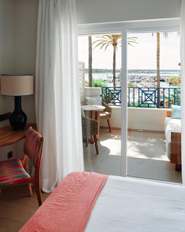 A bright room with a coral throw across white linen and a balcony open to the harbour light